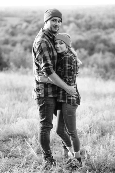 Neşeli adam ve kız parlak örgü şapkalar ve ekose gömleklerle yürüyüşe çıktılar.