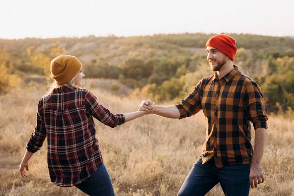 Neşeli adam ve kız parlak örgü şapkalar ve ekose gömleklerle yürüyüşe çıktılar.