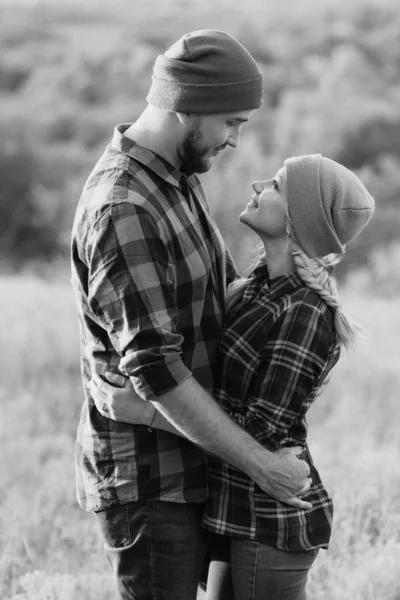 Neşeli adam ve kız parlak örgü şapkalar ve ekose gömleklerle yürüyüşe çıktılar.