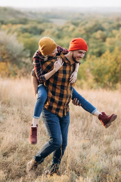 Neşeli adam ve kız parlak örgü şapkalar ve ekose gömleklerle yürüyüşe çıktılar.