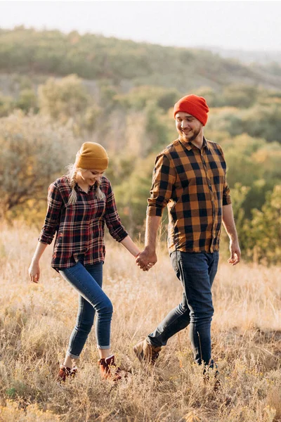 Neşeli adam ve kız parlak örgü şapkalar ve ekose gömleklerle yürüyüşe çıktılar.