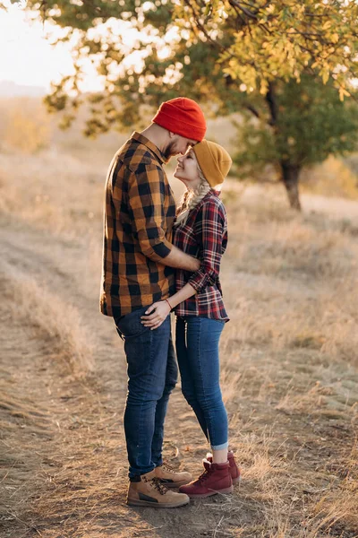 Neşeli adam ve kız parlak örgü şapkalar ve ekose gömleklerle yürüyüşe çıktılar.