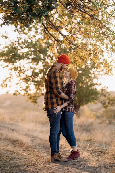 Neşeli adam ve kız parlak örgü şapkalar ve ekose gömleklerle yürüyüşe çıktılar.