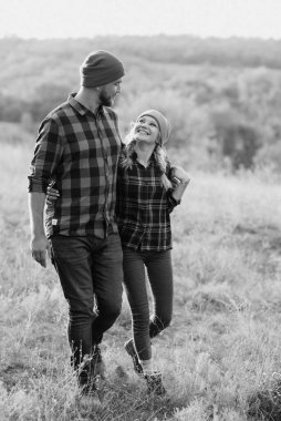 Neşeli adam ve kız parlak örgü şapkalar ve ekose gömleklerle yürüyüşe çıktılar.