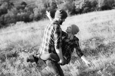 Neşeli adam ve kız parlak örgü şapkalar ve ekose gömleklerle yürüyüşe çıktılar.