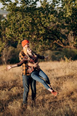 Neşeli adam ve kız parlak örgü şapkalar ve ekose gömleklerle yürüyüşe çıktılar.