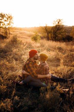 Neşeli adam ve kız parlak örgü şapkalar ve ekose gömleklerle yürüyüşe çıktılar.