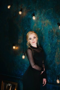 Siyah elbiseli, koyu turkuazlı mavi gözlü sarışın kız.