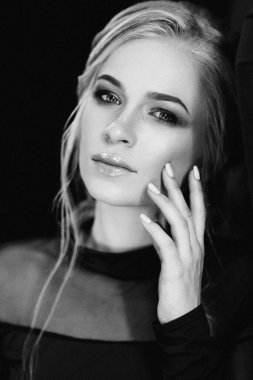 Siyah elbiseli, koyu turkuazlı mavi gözlü sarışın kız.