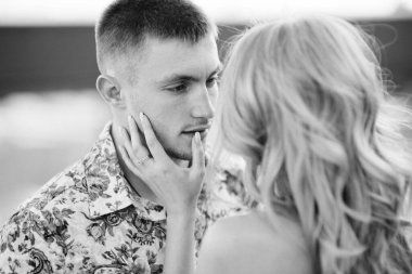 Açık mavi elbiseli sarışın bir kız ve açık tişörtlü bir adam ve granit ocağında kısa şort.