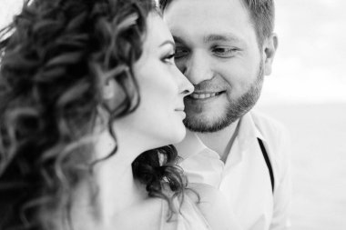 Genç çift, siyah pantolonlu bir adam ve pembe elbiseli bir kız çölün beyaz kumu boyunca yürüyorlar.