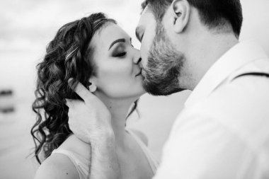 Genç çift, siyah pantolonlu bir adam ve pembe elbiseli bir kız çölün beyaz kumu boyunca yürüyorlar.