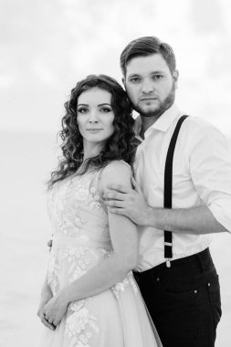 Genç çift, siyah pantolonlu bir adam ve pembe elbiseli bir kız çölün beyaz kumu boyunca yürüyorlar.