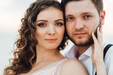 Genç çift, siyah pantolonlu bir adam ve pembe elbiseli bir kız çölün beyaz kumu boyunca yürüyorlar.