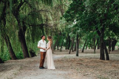 Bir adam ve bir kız, orman ve söğütlerle kaplı vahşi bir nehrin kıyısında yürüyorlar.