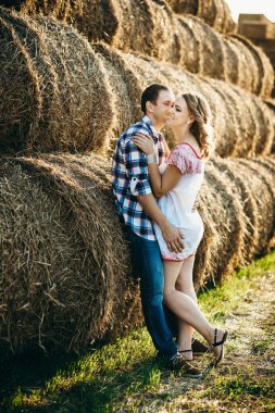 Bir kızla yaz yürüyüşüne çıkan bir adam samanlıkların yanındaki tarlada