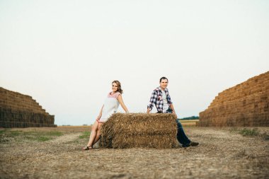 Bir kızla yaz yürüyüşüne çıkan bir adam samanlıkların yanındaki tarlada