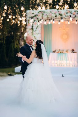 Gelin ve damadın ilk dansı açık hava restoranında ağır beyaz dumanla