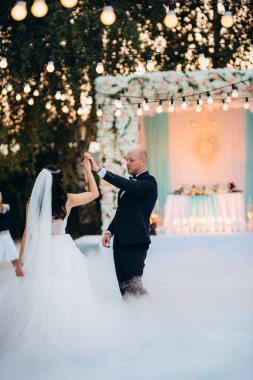 Gelin ve damadın ilk dansı açık hava restoranında ağır beyaz dumanla