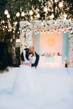 Gelin ve damadın ilk dansı açık hava restoranında ağır beyaz dumanla