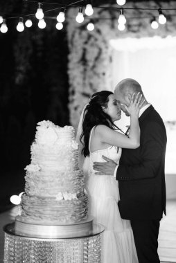 Yeni evliler mutlu bir şekilde kesiyor, gülüyor ve mavi düğün pastasını tadıyor.