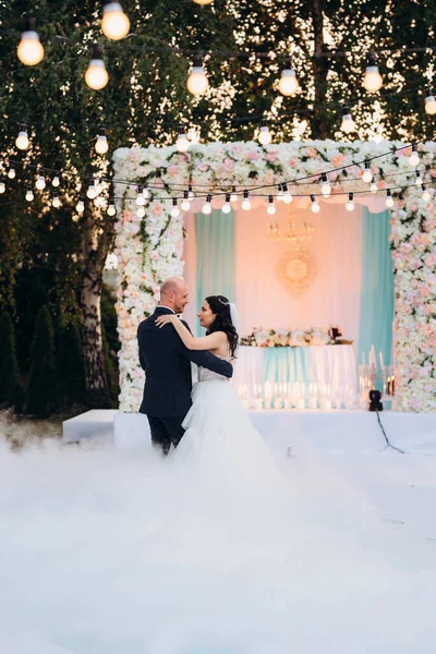 Gelin ve damadın ilk dansı açık hava restoranında ağır beyaz dumanla