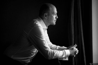 Evin içinde ve dışarıda mavi takım elbiseli ve papyonlu genç bir damadın portresi.