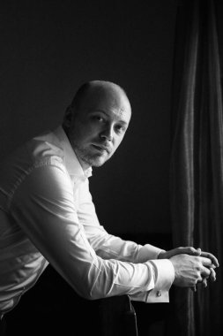 Evin içinde ve dışarıda mavi takım elbiseli ve papyonlu genç bir damadın portresi.