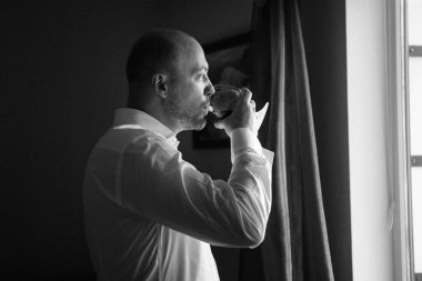 Evin içinde ve dışarıda mavi takım elbiseli ve papyonlu genç bir damadın portresi.