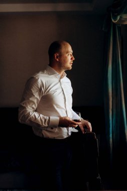 Evin içinde ve dışarıda mavi takım elbiseli ve papyonlu genç bir damadın portresi.