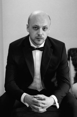 Evin içinde ve dışarıda mavi takım elbiseli ve papyonlu genç bir damadın portresi.