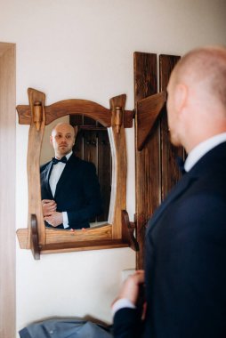 Evin içinde ve dışarıda mavi takım elbiseli ve papyonlu genç bir damadın portresi.