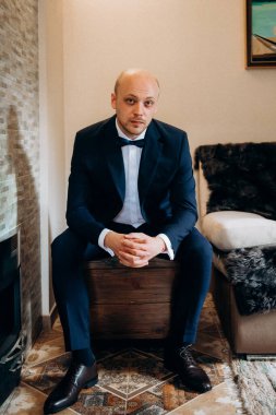 Evin içinde ve dışarıda mavi takım elbiseli ve papyonlu genç bir damadın portresi.