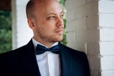 Evin içinde ve dışarıda mavi takım elbiseli ve papyonlu genç bir damadın portresi.