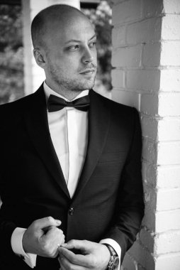 Evin içinde ve dışarıda mavi takım elbiseli ve papyonlu genç bir damadın portresi.