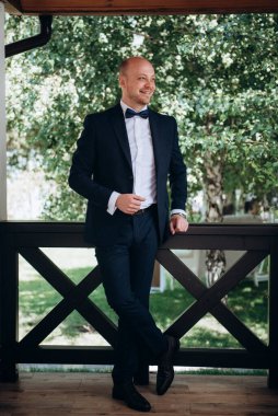 Evin içinde ve dışarıda mavi takım elbiseli ve papyonlu genç bir damadın portresi.