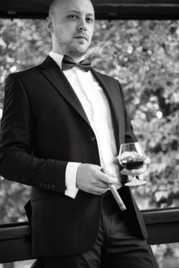 Evin içinde ve dışarıda mavi takım elbiseli ve papyonlu genç bir damadın portresi.