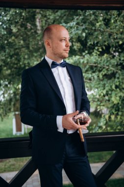 Evin içinde ve dışarıda mavi takım elbiseli ve papyonlu genç bir damadın portresi.