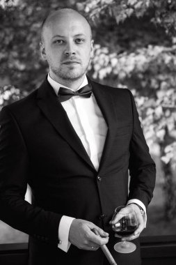 Evin içinde ve dışarıda mavi takım elbiseli ve papyonlu genç bir damadın portresi.