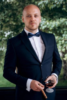 Evin içinde ve dışarıda mavi takım elbiseli ve papyonlu genç bir damadın portresi.