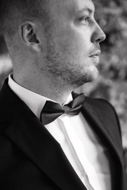 Evin içinde ve dışarıda mavi takım elbiseli ve papyonlu genç bir damadın portresi.