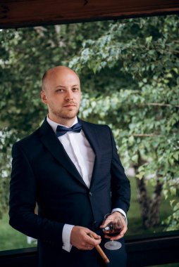 Evin içinde ve dışarıda mavi takım elbiseli ve papyonlu genç bir damadın portresi.