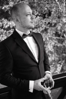 Evin içinde ve dışarıda mavi takım elbiseli ve papyonlu genç bir damadın portresi.