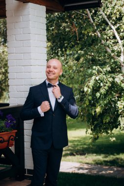 Evin içinde ve dışarıda mavi takım elbiseli ve papyonlu genç bir damadın portresi.