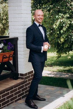 Evin içinde ve dışarıda mavi takım elbiseli ve papyonlu genç bir damadın portresi.