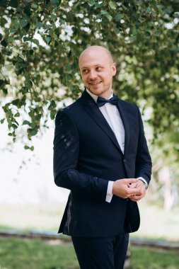 Evin içinde ve dışarıda mavi takım elbiseli ve papyonlu genç bir damadın portresi.