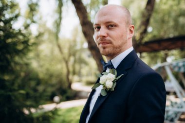 Evin içinde ve dışarıda mavi takım elbiseli ve papyonlu genç bir damadın portresi.