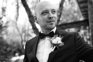 Evin içinde ve dışarıda mavi takım elbiseli ve papyonlu genç bir damadın portresi.