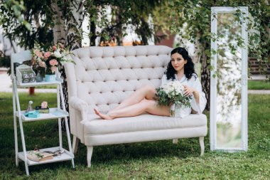 Siyah saçlı gelin evlenmeye hazırlanıyor. Bahçedeki bir yatak odasında.