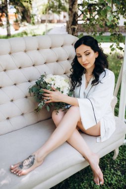 Siyah saçlı gelin evlenmeye hazırlanıyor. Bahçedeki bir yatak odasında.